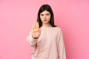 Young Ukrainian teenager girl over isolated pink background making stop gesture