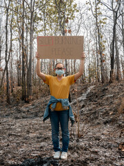 A female volunteer holding a nature conservation banner in area of the burning forest and...