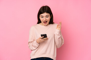 Young Ukrainian teenager girl over isolated pink background surprised and sending a message