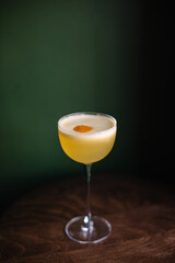 Whiskey sour cocktail decorated with lemon zest. Green color background.	