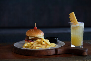 burger and fries with black background and pineapple juice