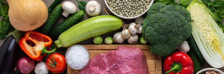 Fresh farm organic vegetables banner, healthy food concept, vegetables and mushrooms, superfoods and beans around the board with a large fresh piece of beef fillet, top view
