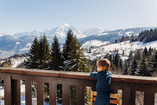 petit gar&ccedil;on observe la vue de son balcon sur la montagne au ski