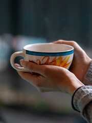 Manos de mujer sosteniendo taza de café de flores