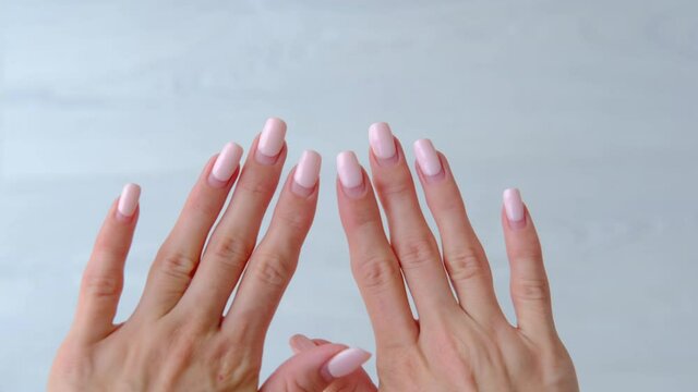 Female hands with old worn long lasting painted nails with  pastel pink gel polish cover.  Overgrown manicure. Time for correction gel polish. Nail care concept. Woman shows regrowth of her nails.