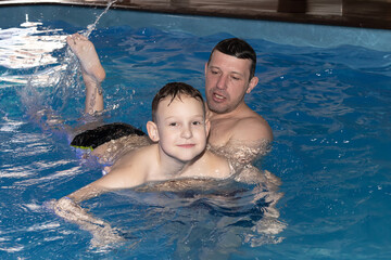 A Dad and son learn to swim in the pool