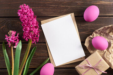 Easter holiday card with copy space, colored eggs gift box and hyacinth flowers on wooden background