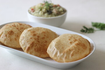 Deep fried indian flat bread served with mixed vegetable curry in a coconut cashew gravy