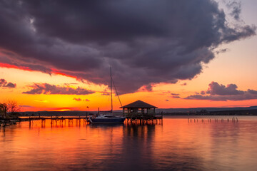 Fototapeta na wymiar Beautiful sunset view at wooden jetty and boat.