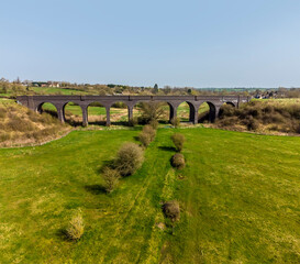 Fototapeta na wymiar An aerial view across the fields towards the abandoned railway viaduct near to Helmdon, Northamptonshire, UK on a bright Spring day