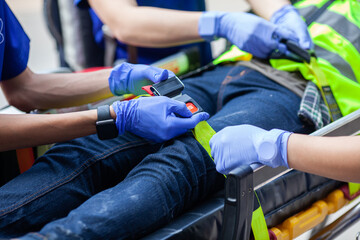 Selective focus of paramedic team locking belt near patient on stretcher for moving.