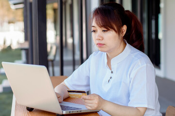 Fototapeta premium Online Payment . Asian woman holding credit card and using laptop with online shopping. Home shopping