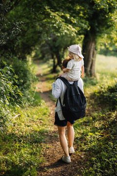 Petite fille sur les &eacute;paules de sa maman lors d'une balade &agrave; la campagne
