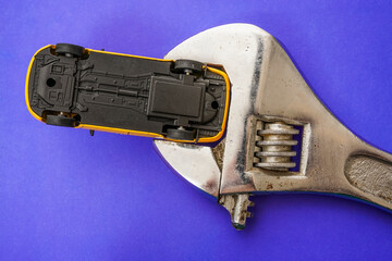 yellow taxi car in iron wrench isolated on blue background. bottom of car.