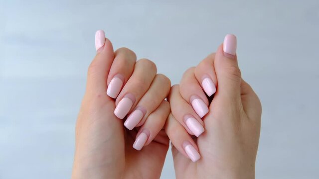 Female hands with old worn long lasting painted nails with pastel pink gel polish cover. Overgrown manicure. Time for correction gel polish. Nail care concept. Woman shows regrowth of her nails.