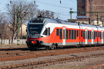 Naklejka premium Untitled red passenger train arrival at railway train station. Platform track front view.