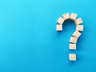 Question mark made of wooden blocks with copy space on blue background