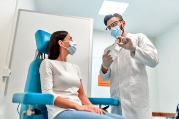 Vaccination, immunization campaign, disease prevention concept. A woman wearing a medical mask receives the Covid-19 vaccine in a doctor's office. The nurse talks about the vaccine to the patient.