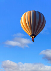 Flying beautiful hot air balloon with a basket of tourists in the blue sky. Close-up, copy space.