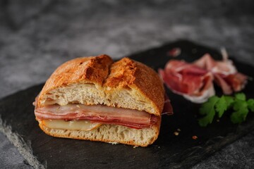 Simple Prosciutto ciabatta sandwich on dark moody setting - obrazy, fototapety, plakaty