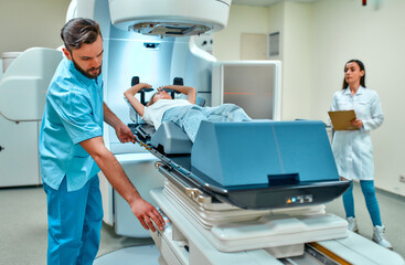 A young woman is undergoing radiation therapy for cancer under the supervision of doctors in a modern cancer hospital. Cancer therapy, advanced medical linear accelerator.