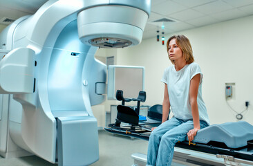 A young woman is undergoing radiation therapy for cancer in a modern cancer hospital. Cancer treatment, modern medical linear accelerator.