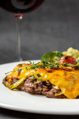 Cheddar cheese beefsteak with potatoes and broccoli on dark stone background