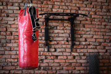 Old punching bag and boxing gloves on the brick wall background.