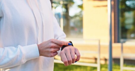 Close up of digital smart watch on woman's Caucasian hand. Beautiful adult female athlete using stopwatch to time jogging results in urban city street. Sport, healthy lifestyle concept. - Powered by Adobe