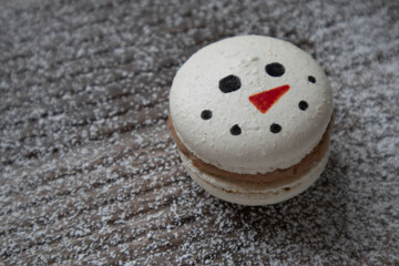 Macaron cookie decorated with a snowman face