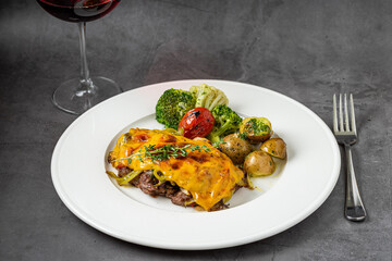 Cheddar cheese beefsteak with potatoes and broccoli on dark stone background