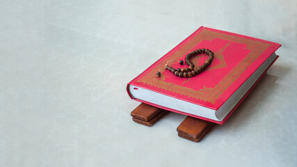 Misbaba the holy wooden rosary beads on top of the quaran book with copy space.
