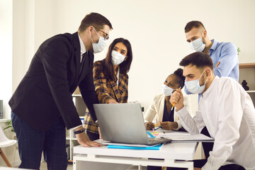 Obraz premium Creative interracial business team meeting after covid-19 lockdown in new normal office. People partner in protective medical mask coworking brainstorming discussing online project at safe workplace