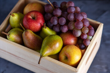 fresh assorted fruits in a wooden box, pears, apples, grapes, close-up