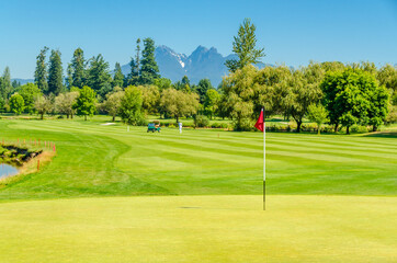 Obraz premium Golf course with gorgeous green and pond.