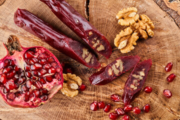 slicing Churchkhela, pomegranate and nuts on a wooden background, top view, serving
