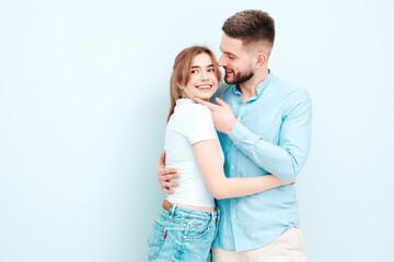 Smiling beautiful woman and her handsome boyfriend. Happy cheerful family having tender moments near light blue wall in studio.Pure cheerful models hugging.Embracing each other