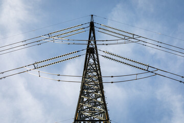 high part of high voltage power line tower with blue sky and some light clouds