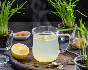 Ginger tea with lemon in a glass mug on a dark concrete background.