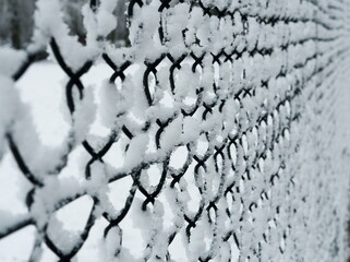 Metal fence covered with snow. close-up on icy wire fence
