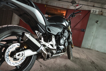 A motorcycle is being parked in a warm garage for the winter. Right side of the motorcycle.
