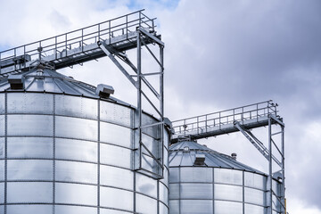 Granary elevator. Silver silos on agro-processing and manufacturing plant for processing drying cleaning and storage of agricultural products, flour, cereals and grain.