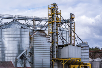 Fototapeta na wymiar Granary elevator. Silver silos on agro-processing and manufacturing plant for processing drying cleaning and storage of agricultural products, flour, cereals and grain.