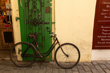 Bicicleta antigua aparcada sobre puerta de madera verde.