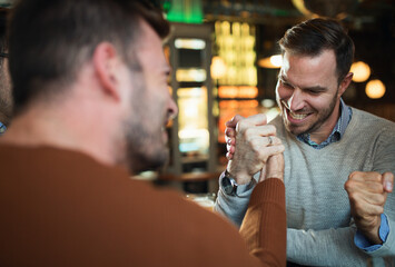 Friends arm wrestling at bar