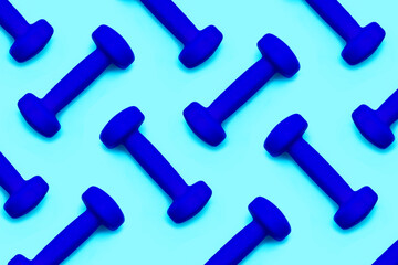 Lots of blue dumbbells isolated on light blue background. Pattern. Healthy lifestyle. Sport...