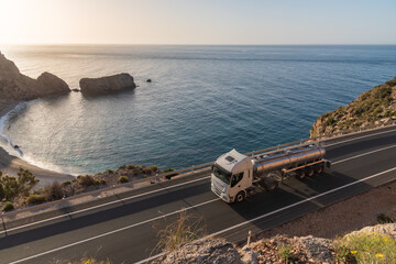 Tank truck driving on a mountain road by the sea.
