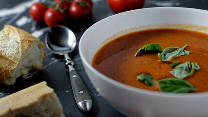 Close up of bowl with tomato soup and baguette