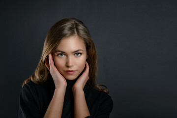 beautiful young girl in a black jacket on a black background copy space. portrait of a beautiful blonde woman