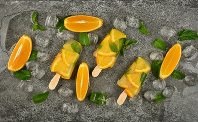Orange and mint ice cream popsicles on table